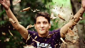 a blurred photo of a young man throwing leaves into the air in a woodland areas