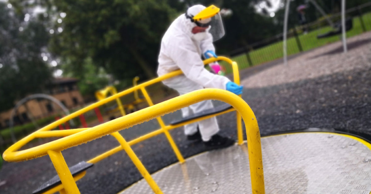 Man in white overalls cleaning park equipment