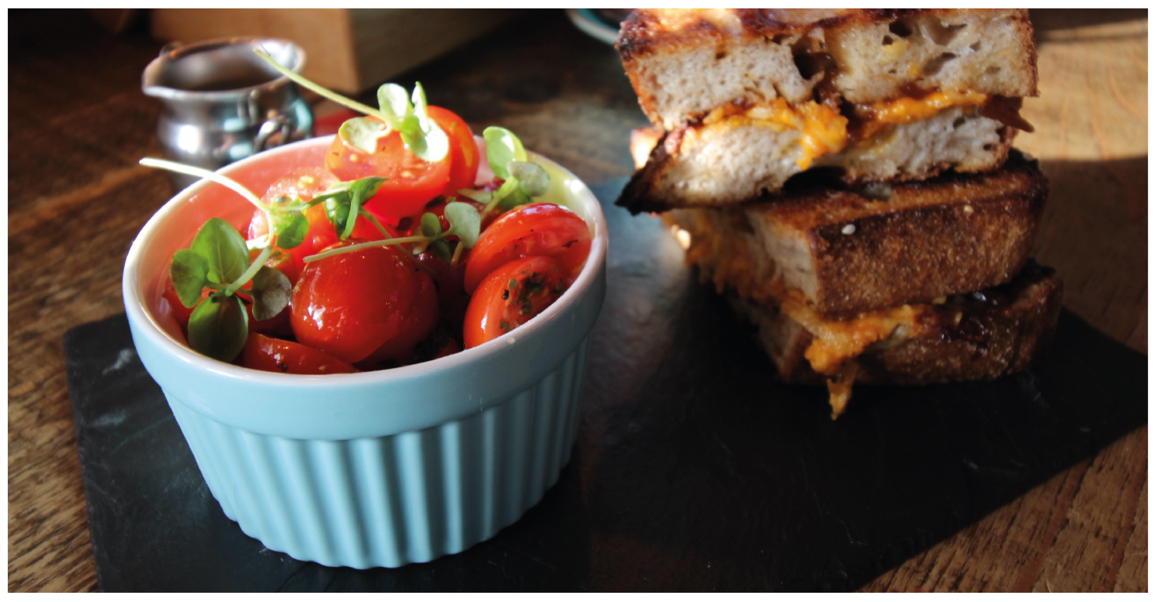 a toasted cheese sandwich with a small portion of cherry tomatoes next to it